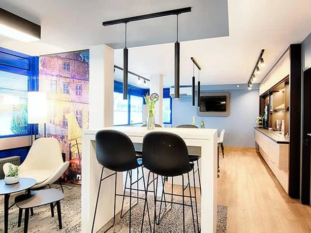 Ein modernes Wohnzimmer mit offenem Küchenbereich. Helle Farben und eine gemütliche Atmosphäre.