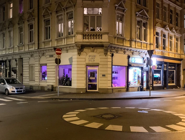 Modularfield Der Eingangsbereich eines Eckhauses bei Nacht, beleuchtet von lilafarbenem Licht.The entrance area of a corner house at night, illuminated by purple light.