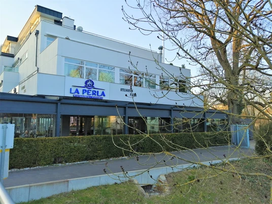 Ristorante La Perla Herford_Pro Herford GmbH.jpg Moderne weiße Gebäude Fassade des italienischen Restaurants La Perla mit verglaster Terrasse und Baum.