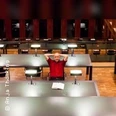 Eine Person sitzt entspannt an einem großen Tisch in einer modernen, gut beleuchteten Bibliothek.