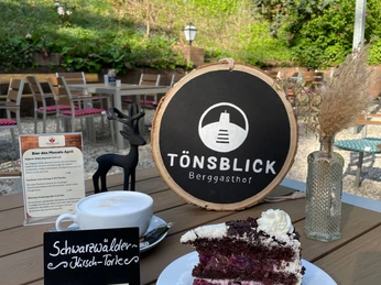 Berggasthof Tönsblick, Oerlinghausen Schwarzwälder Kirschtorte und Kaffee auf einem Holztisch auf der Terrasse vom Berggasthof Tönsblick.