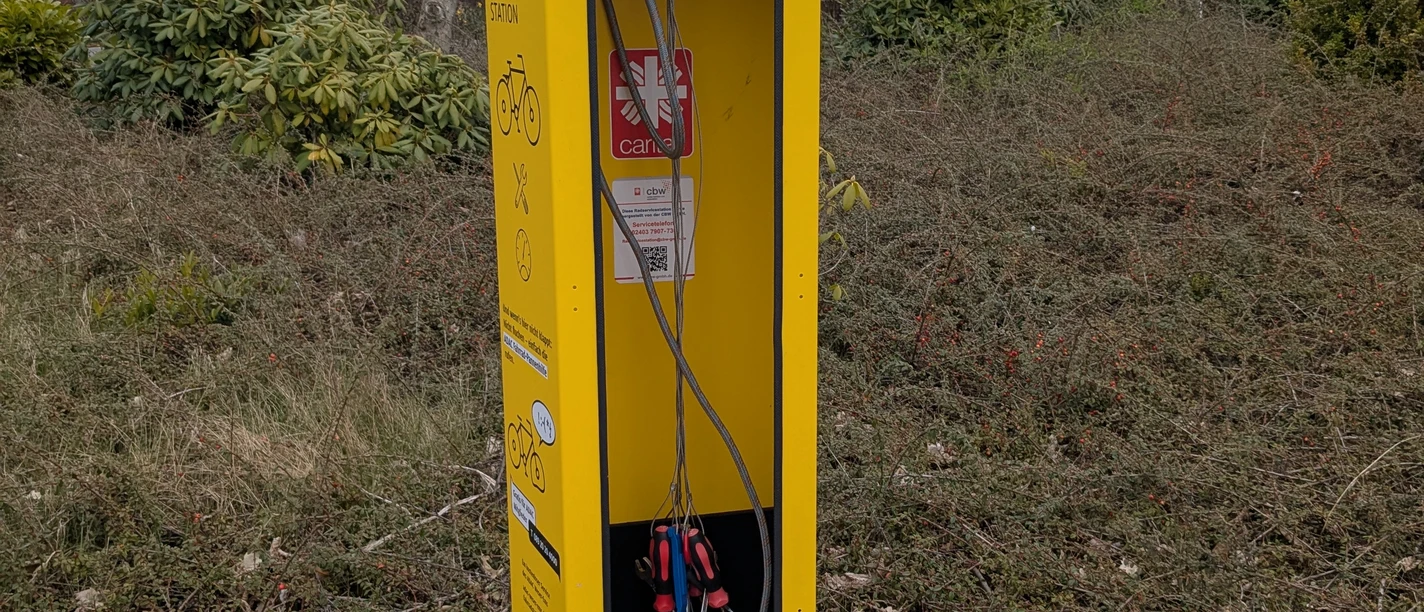 reparatursäule.werdum.jpg Gelbe Reparatursäule für Fahrräder mit Werkzeugen an langen Schnüren