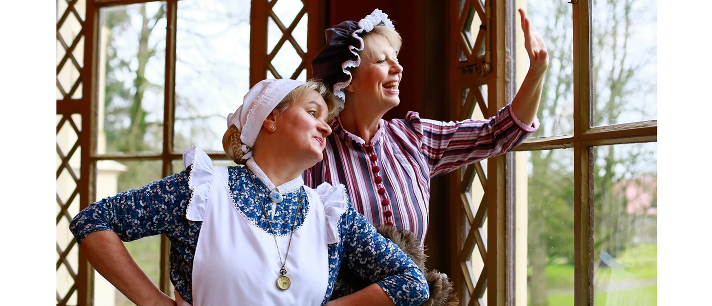 Trientje und Gertrude Das Bild zeigt zwei Frauen in traditioneller Kleidung. Sie strahlen Freude und Begeisterung aus.