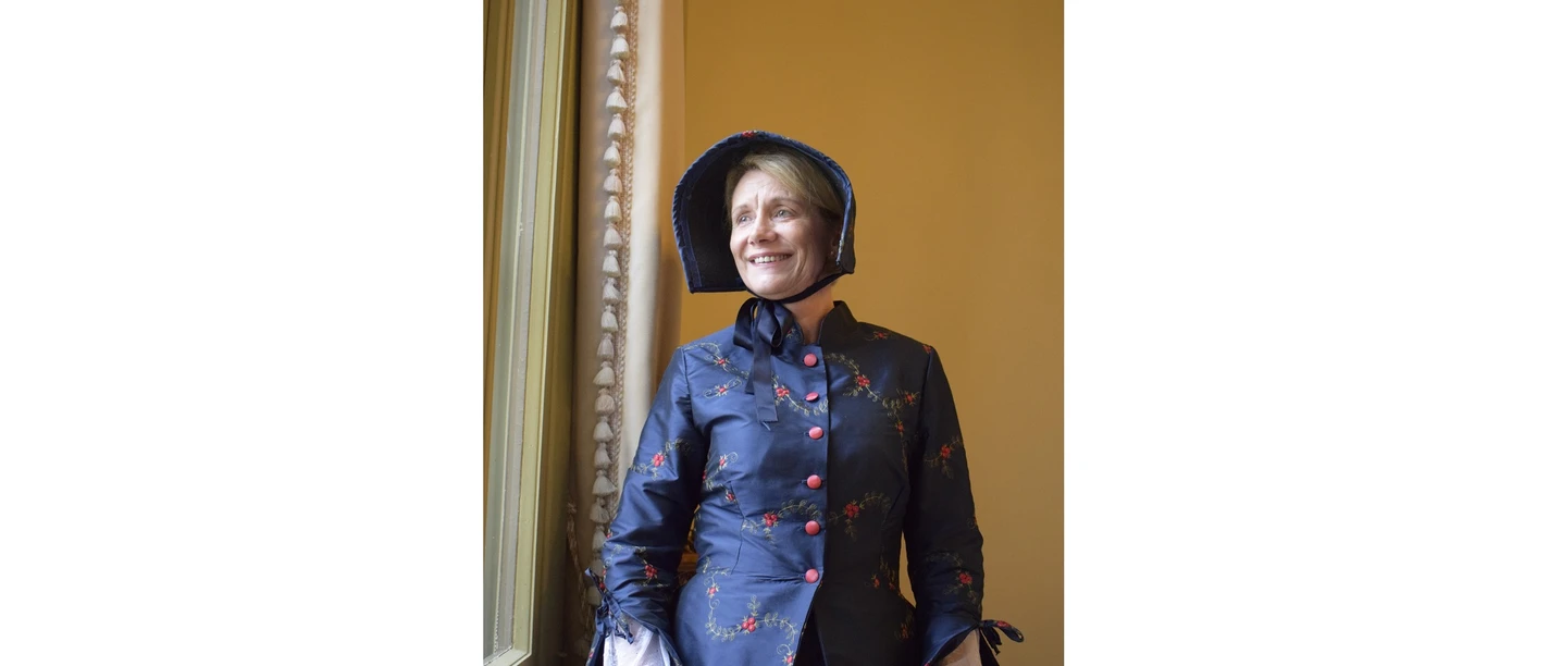 Hildur Kostümierte Schlossführerin lächelt im historischen Kostüm vor altem Fenster.