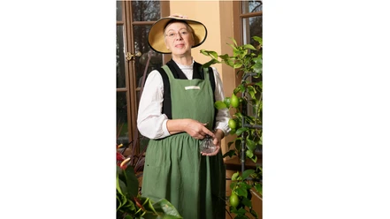 Costumed castle guide with straw hat in a greenhouse.