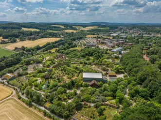 Luftaufnahme des Osnabrücker Zoos Luchtfoto van een uitgestrekt, groen landschap met gebouwen en velden op de achtergrond.