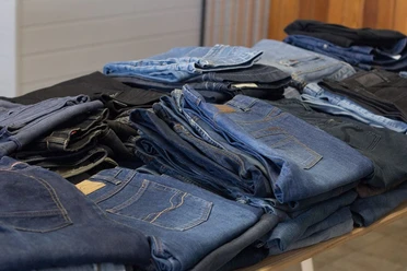 Second Hand Bekleidung (c) Pixabay.jpg Verschiedene Jeanshosen liegen gestapelt und nebeneinander auf einem Tisch.