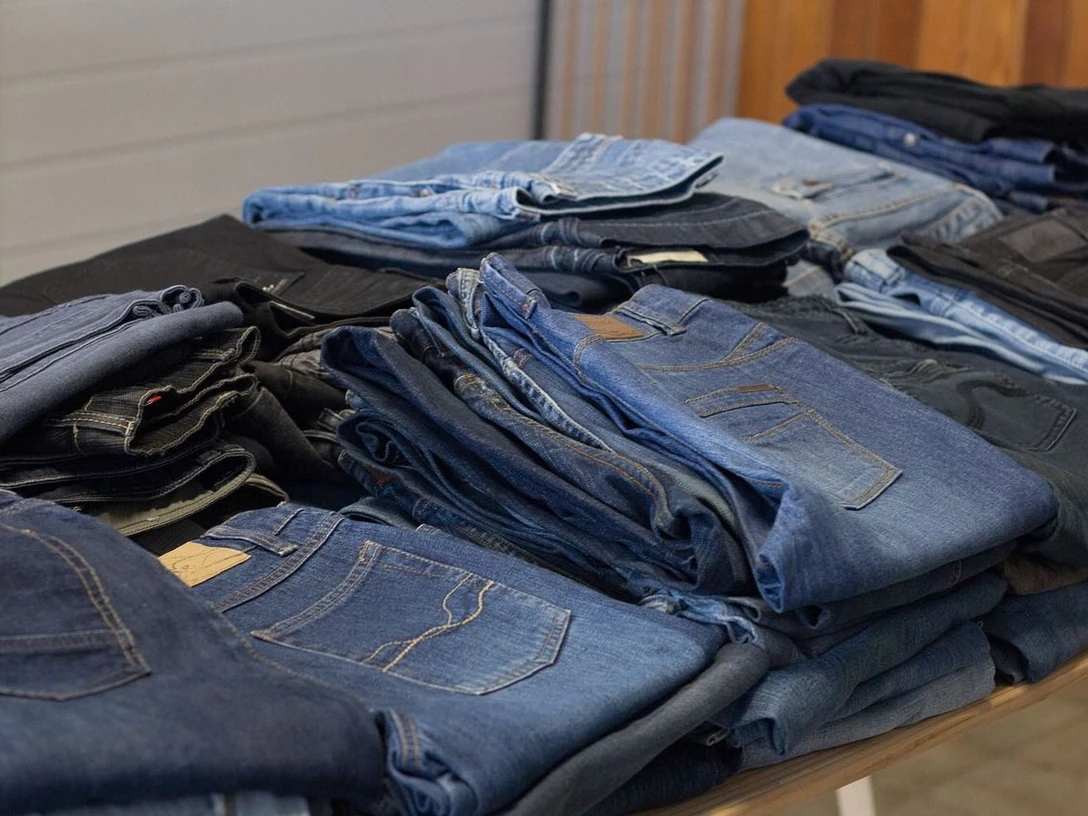 Second Hand Bekleidung (c) Pixabay.jpg Verschiedene Jeanshosen liegen gestapelt und nebeneinander auf einem Tisch.