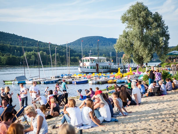 Schiedersee Menschen am Strand © T.Liebold.jpg Strandbesucher am Schiedersee entspannen, während Segelboote und ein Ausflugsdampfer vorbeiziehen.