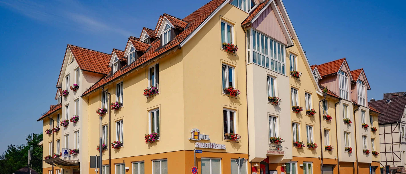 Außenansicht des dreistöckigen Hotels , gelb gestrichen mit Blumenkästen