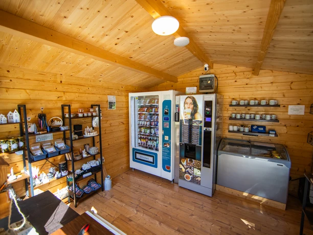 In't Euwer Kleines Holzhaus mit Verkaufsautomaten, Regalen voller regionaler Produkte und einer Eisvitrine.