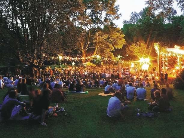 Die Freilichtbühne in der Mülheimer Altstadt Freilichtbühne in Mülheim an der Ruhr bei Abenddämmerung, mit Publikum in dichter Baumkulisse.