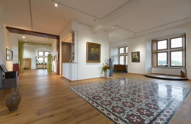 Ein helles Museum mit großen Fenstern, modernen Elementen und traditionellen Kunstwerken in einem großzügigen Raum.