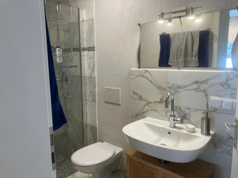 Fewo Am Johannistor.jpg Modernes Badezimmer mit Marmordekor, großer Dusche, Waschbecken und WC, geschmackvoll eingerichtet.