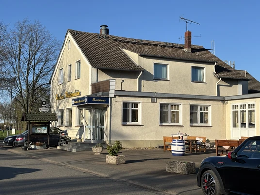 Rasthaus Wietersheim Ein zweistöckiges Restaurant mit heller Fassade und traditionellem Schild, umgeben von Parkplätzen.