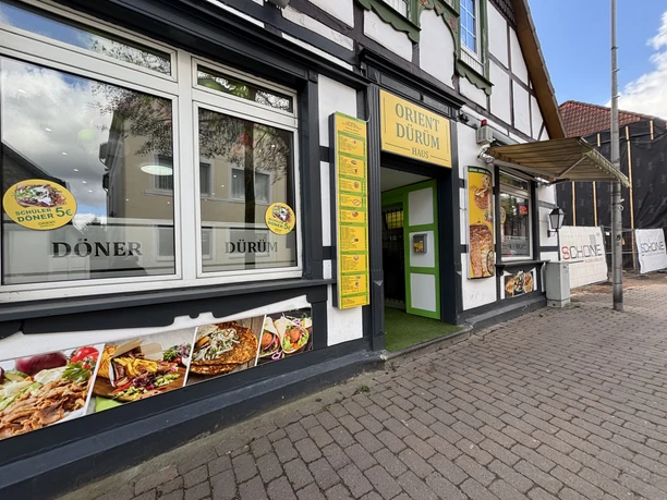 Orient Dürüm Haus: Außenansicht mit gelbem Eingang und Fotocollage von Dürüm-Spezialitäten.