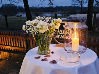 Café Weserscheune Ein mit Blumen und Kerzen dekorierter Tisch vor dem Café Weserscheune bei abendlicher Beleuchtung.