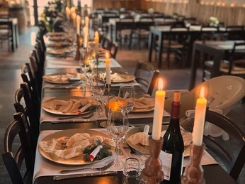Ein festlich gedeckter Tisch in einem Restaurant, beleuchtet von warmen Kerzen, versprüht festliche Stimmung.