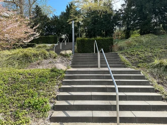 Kneipp-Venentreppe mit Metallgeländern im Kurpark, umgeben von Grün und Blüten