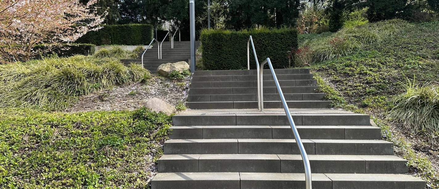 Kneipp-Venentreppe mit Metallgeländern im Kurpark, umgeben von Grün und Blüten