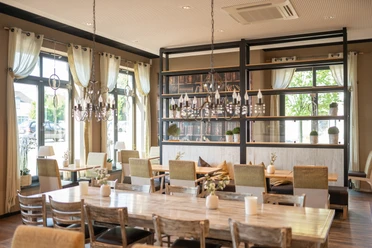 Ferdinands Bäckerei | Restaurant Helle, moderne Innenansicht eines Restaurants mit großen Fenstern, Holztischen und eleganter Beleuchtung.