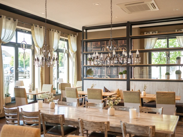 Ferdinands Bäckerei | Restaurant Helle, moderne Innenansicht eines Restaurants mit großen Fenstern, Holztischen und eleganter Beleuchtung.