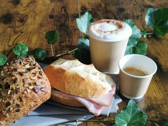 Café et sandwiches au bistrot Rüfenacht Zwei Becher Kaffee, ein Sandwich und ein Körnerbrötchen, arrangiert auf einem HolztischTwo mugs of coffee, a sandwich and a granola roll, arranged on a wooden tableDeux gobelets de café, un sandwich et un petit pain aux graines, disposés sur une table en bois