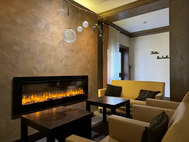 Innenansicht Waldhotel Tropfsteinhöhle Gemütliche Lounge mit Elektrokamin, beigen Sofas und warmem Lichteinfall, perfekte Entspannungsecke.