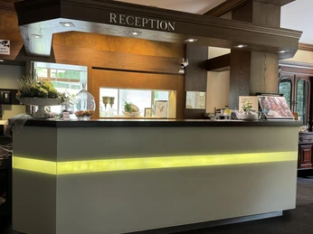 Rezeption - Waldhotel Tropfsteinhöhle Empfangstresen in einem Hotel, modern beleuchtet, mit Dekorationen und einem freundlichen Ambiente.