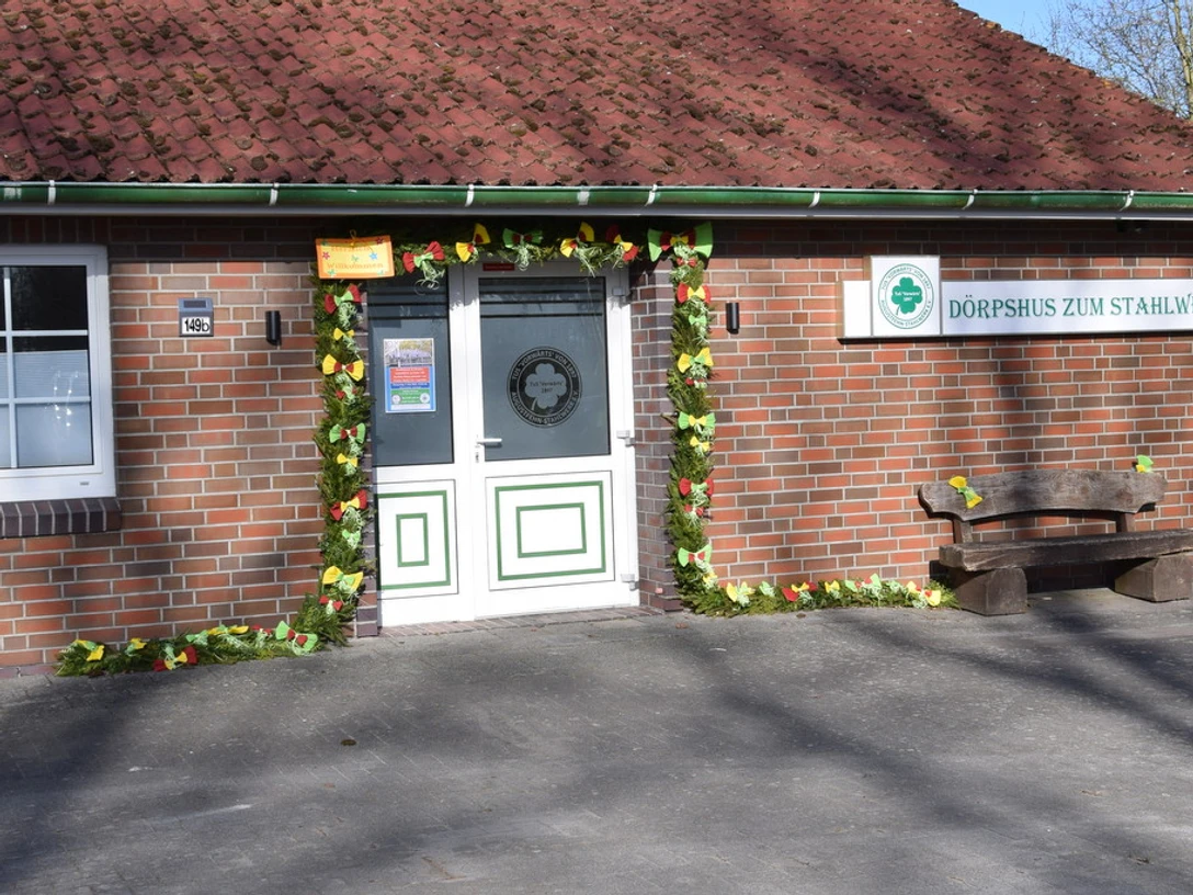 Dörpshus zum Stahlwerk.jpg Zu sehen ist das Dörpshus zum Stahlwerk mit einer einladenden Eingangstür, umrahmt von buntem Laub.