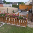 Ferienwohnung Angelmann Ferienwohnung Angelmann: Holzterrasse mit Blumen, Gartenideen und Sitzbereich, umgeben von Zäunen.