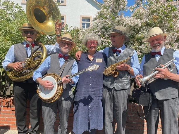 Die_Salzsieder_Jutta_Redecker.jpg Eine fröhliche Jazzband mit fünf älteren Musikern posiert lächelnd unter blühendem Baum.