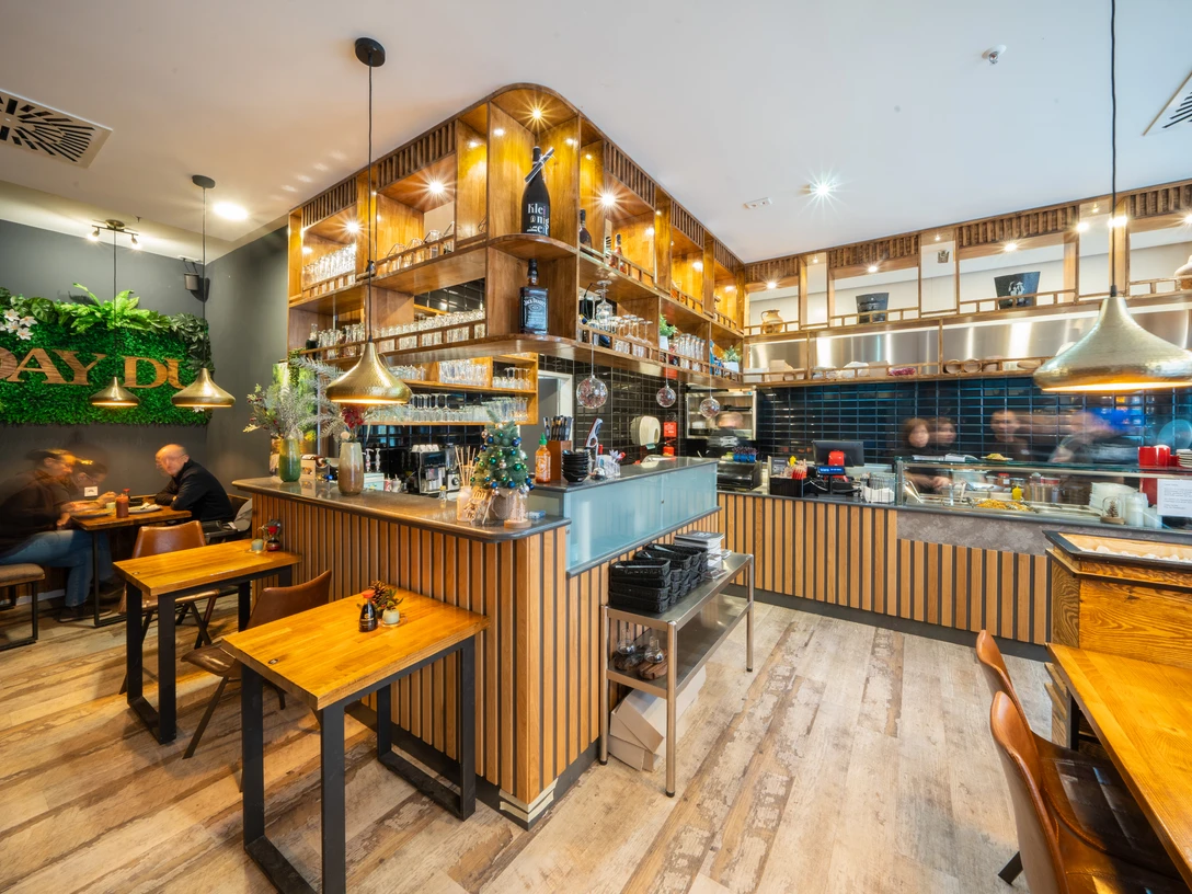 Day Du - Asiatische Spezialitäten Ein asiatisches Restaurant mit Holzmöbeln, modernen Dekorationselementen und einem belebten Ambiente.