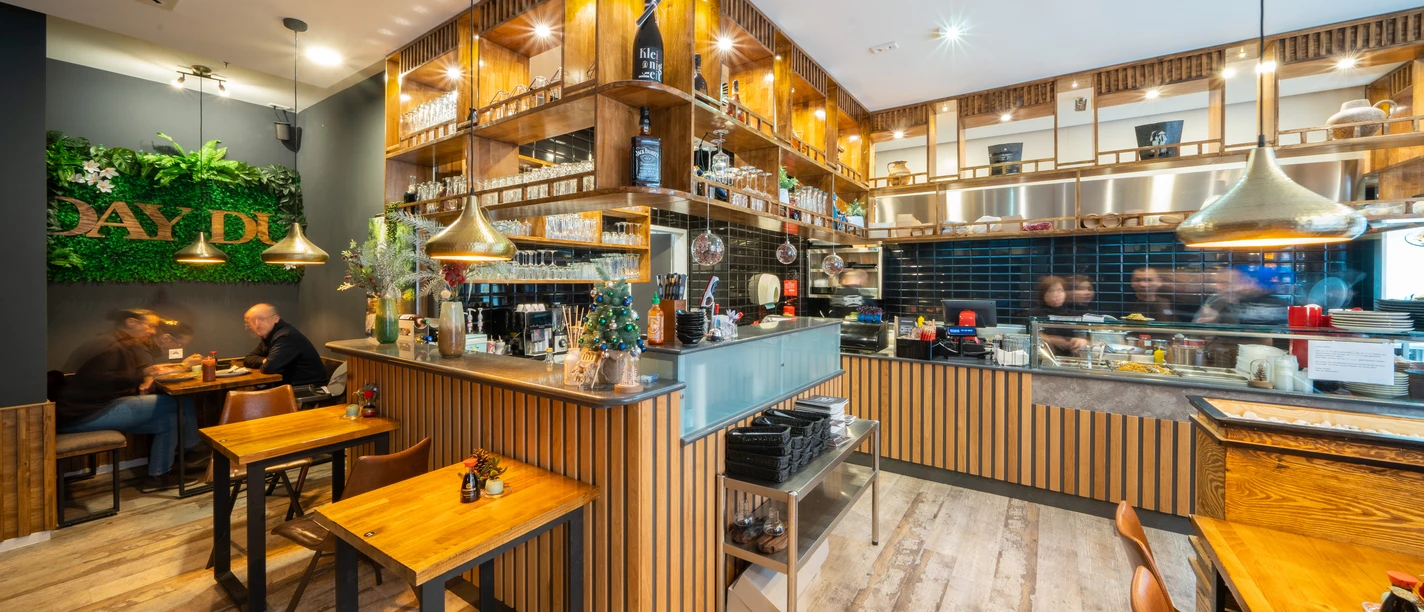 Day Du - Asiatische Spezialitäten Ein asiatisches Restaurant mit Holzmöbeln, modernen Dekorationselementen und einem belebten Ambiente.