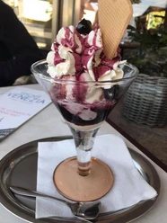 Eiscafé Venezia Ein eleganter Eisbecher mit Sahne, Fruchtsauce und Waffel im Eiscafé Venezia auf einem Tablett serviert.