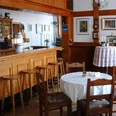 Gaststube (1).JPG Gemütliche Gaststube mit Holzmöbeln, Bartresen und dekorativen Bildern an der Wand.