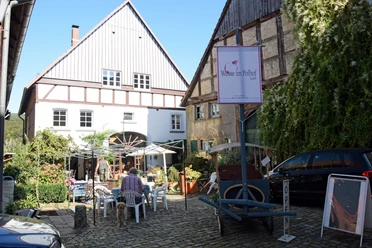 Zwei Häuser im Fachwerkstil mit einem Innenhof. Ein Restaurant bietet Sitzplätze im Freien.