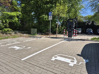 E-Auto-Ladestation mit zwei markierten Stellplätzen auf einem Parkplatz.