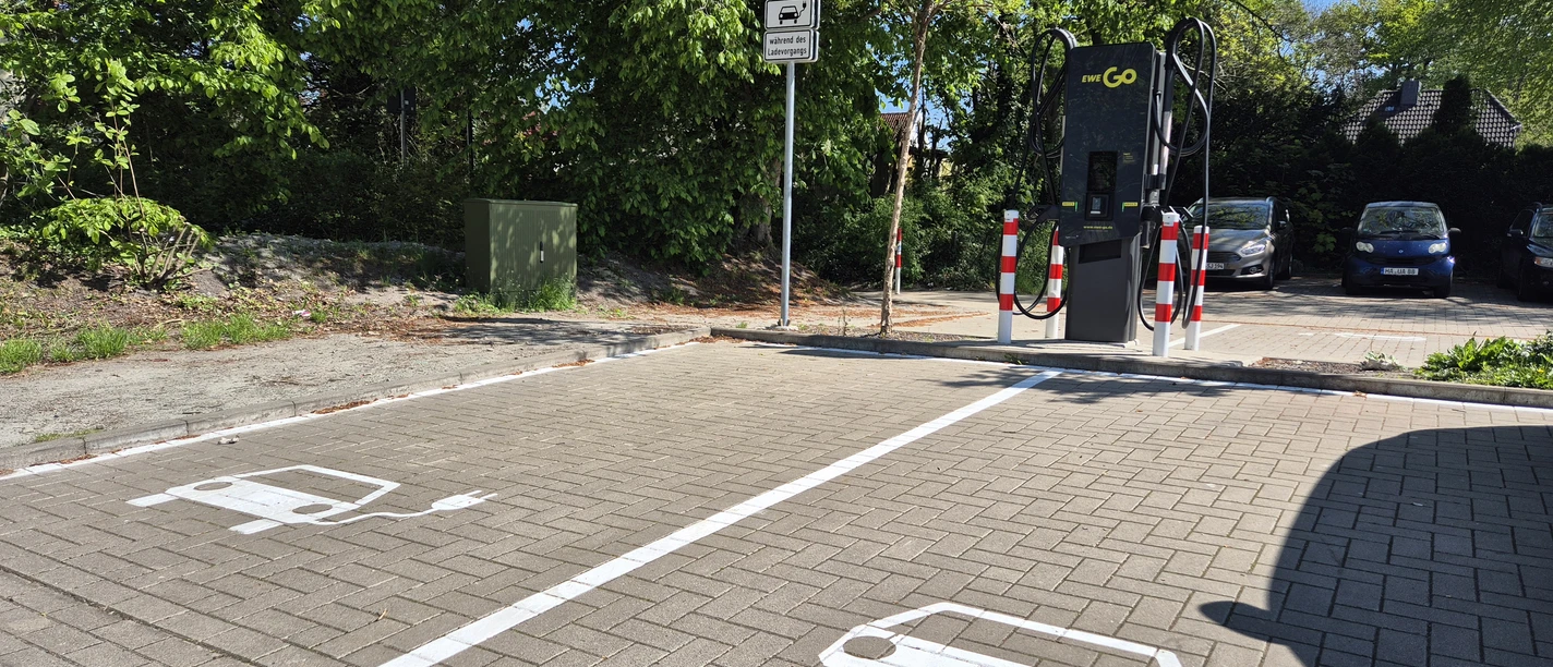 E-Auto-Ladestation mit zwei markierten Stellplätzen auf einem Parkplatz.