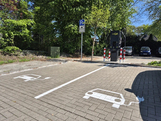 E-Auto-Ladestation mit zwei markierten Stellplätzen auf einem Parkplatz.