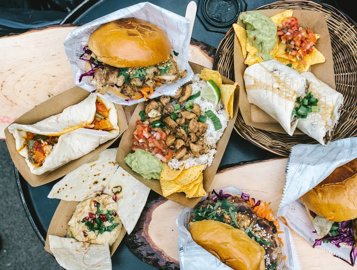 Street Food Festival Köln Verschiedene köstliche Street-Food-Gerichte sind auf einem Holztisch arrangiert.Various delicious street food dishes are arranged on a wooden table.