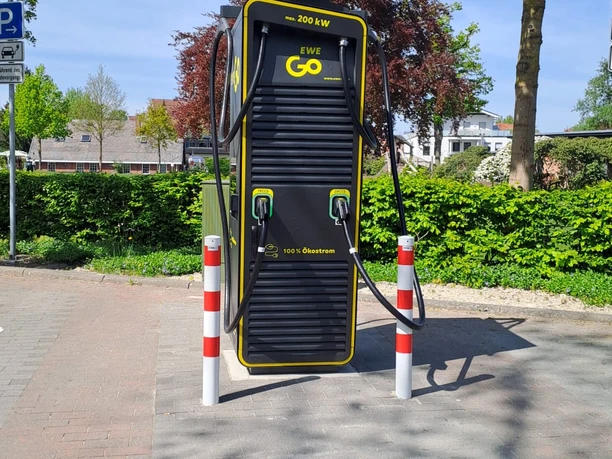 Ladesäule am Kögel-Willms-Platz E-Ladesäule mit zwei Ladeanschlüssen von EWE Go, umgeben von Bäumen und klar blauem Himmel.