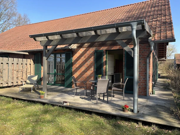 Backsteinhaus mit rotem Ziegeldach im Öspergarten, ausgestattet mit Terrasse und Gartenmöbeln.