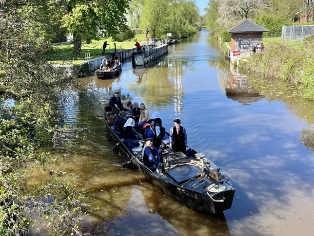 Durch den Gerkenstau Traditionelle Torfkähne mit Menschen in Tracht fahren bei Sonnenschein durch eine Schleuse.