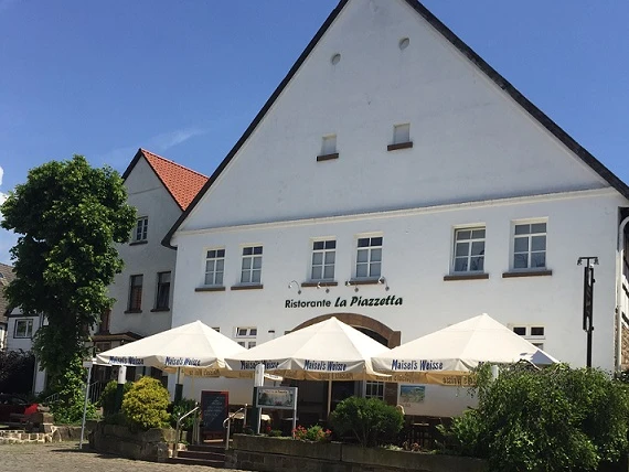 Hausansicht Anno 1700 bearbeitet für web.jpg Historisches Gebäude mit spitzem Giebel, Außenterrasse des Restaurants "Ristorante La Piazzetta".