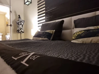 Schlafzimmer.jpg Ein Doppelbett in einem modernen Schlafzimmer, dekoriert mit Kissen, Blick in ein angrenzendes Badezimmer.