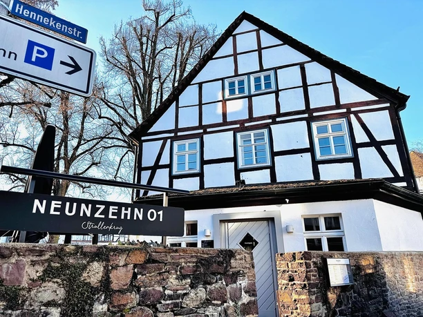 Fachwerkhaus mit Bruchsteinmauer und Werbeschild