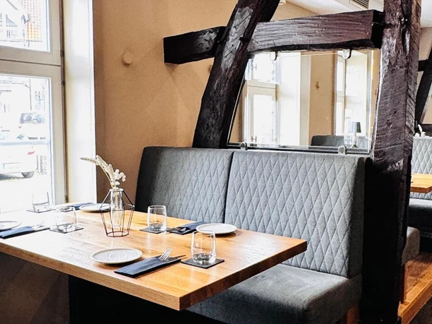 NEUNZEHN01_Restaurant_Nische.jpg Gastraum mit Sitznische mit grauer Polsterbank und sichtbarem Ständerwerk