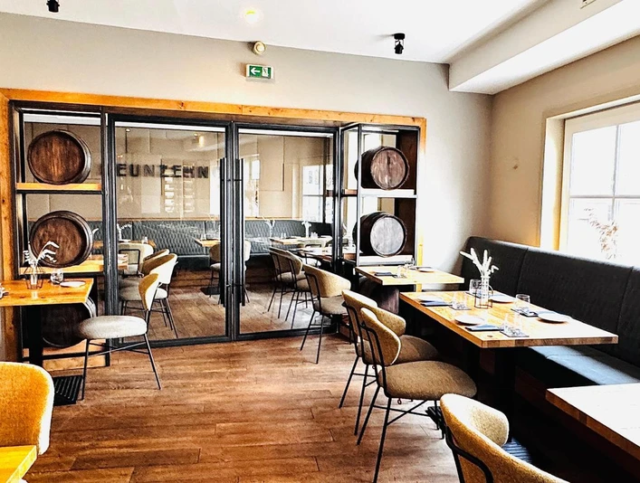NUENZEHN01_Restaurant_hinten.jpg Innenansicht Gastraum mit Holzfußboden, langer Polstersitzbank rechts, Tischen und Stühlen, modern