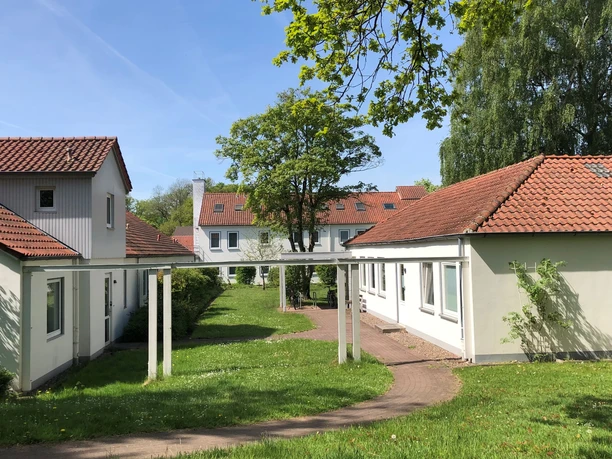 Several white buildings with red roofs and lots of greenery around them make up the grounds of the Protestant Academy Loccum.